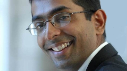 headshot of smiling dark skin male wearing glasses looking over his left shoulder