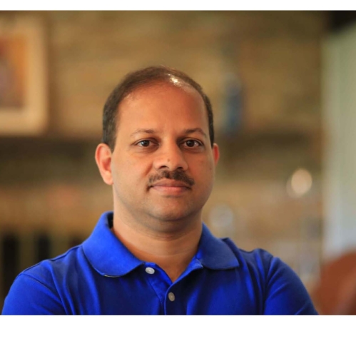 Head shot of Indian male with moustache wearing a blue button down shirt.