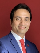 Head shot of Asian male with short black hair wearing a blue suit jacket, white button down shirt, and a red tie.