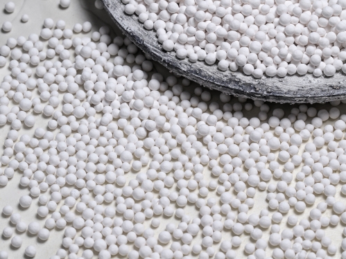 hundreds of small white balls of nickel catalyst against a white background.