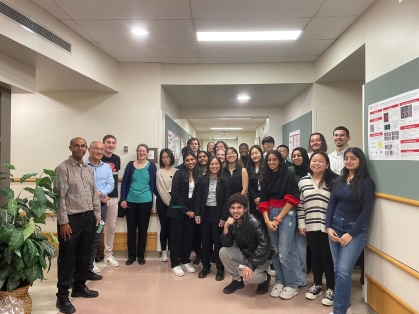 Large group of students and professors stand in hallway.